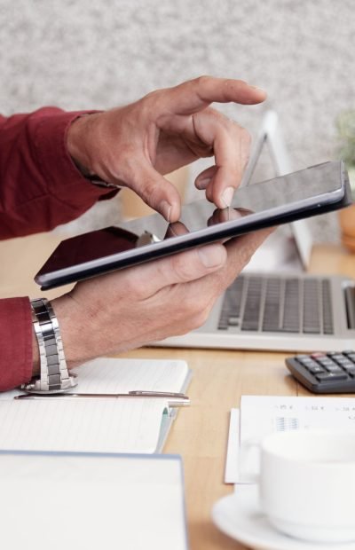 Close-up of businessman sitting at office desk and using digital tablet for work